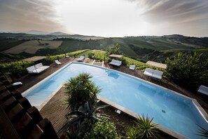 Piscina con sillones de descanso y vistas a colinas ondulantes.