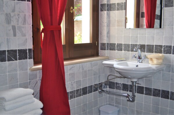 Baño con lavamanos, espejo y ventana con cortinas.