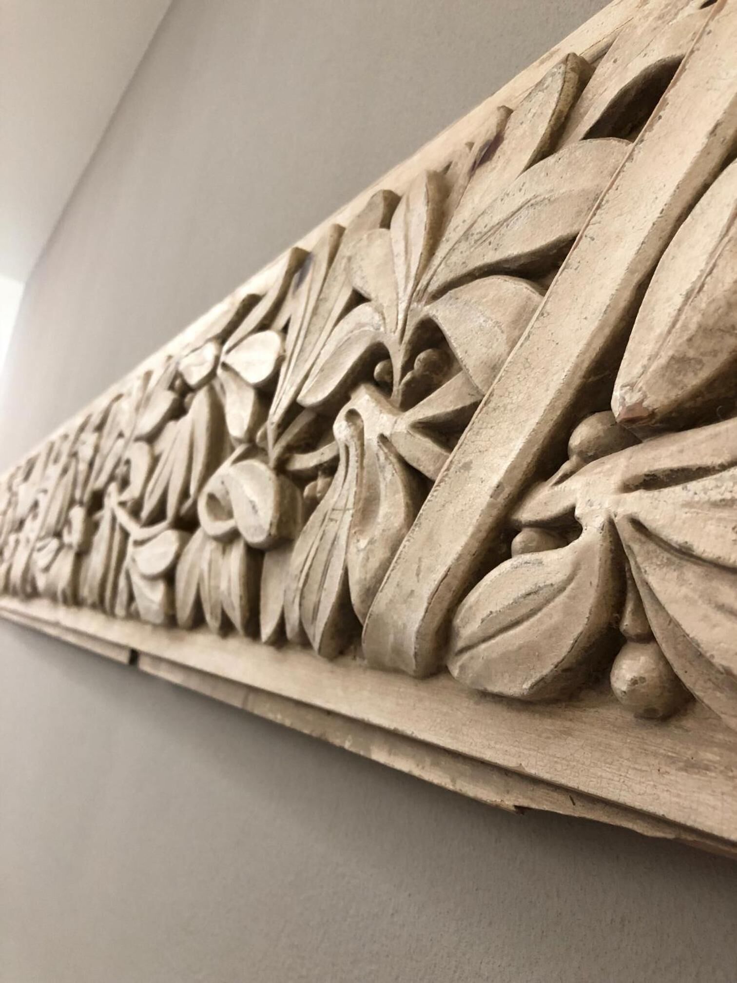 Un panel de madera tallado detalladamente con motivos florales y de hojas.