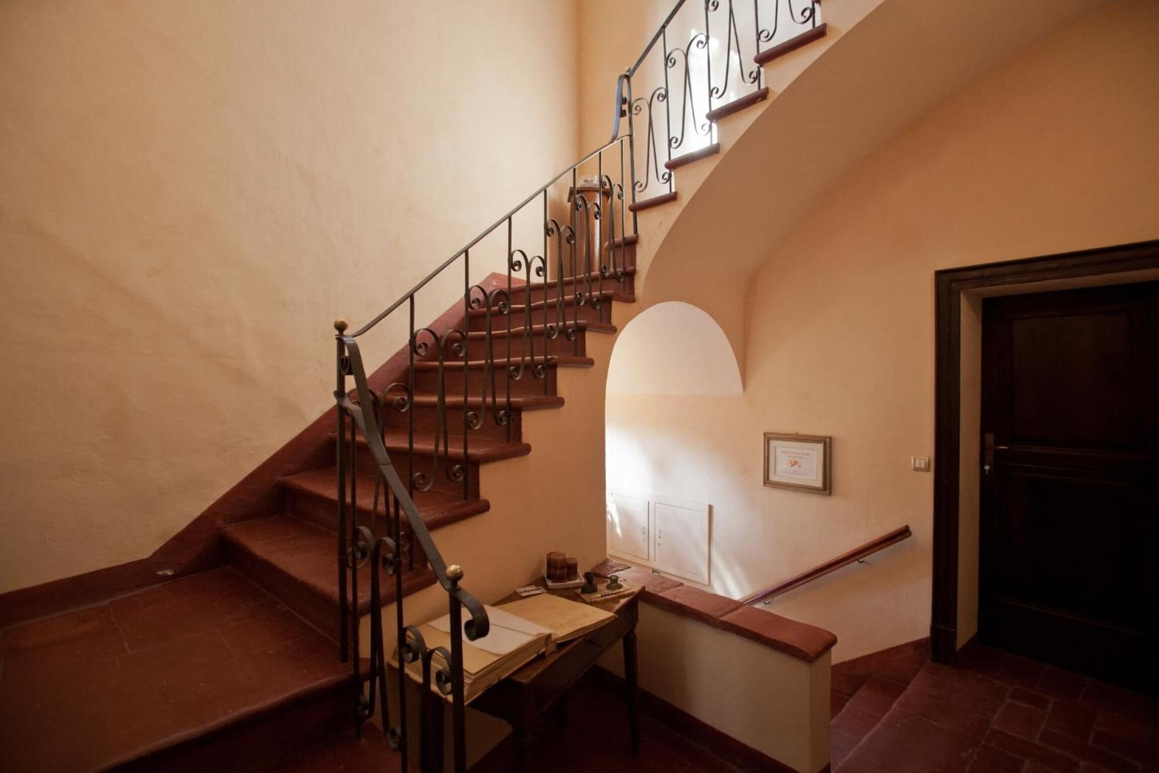 A staircase with ornate metal railings and wooden steps leading to a landing.