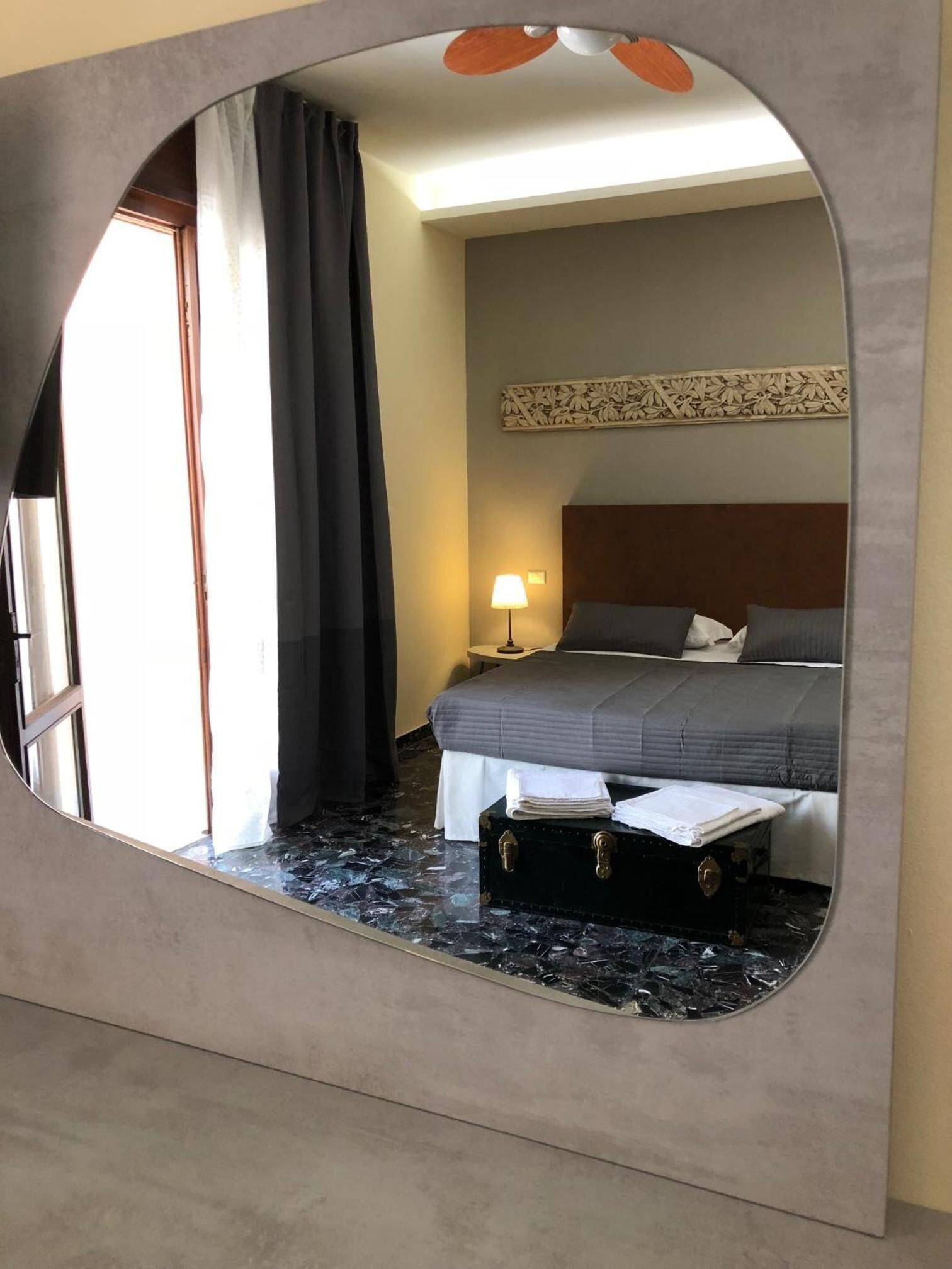 Une chambre d’hôtel comprenant un lit, une table de chevet, une lampe, une valise et un élément décoratif mural.