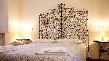 A neatly made bed with a patterned bedspread, two bedside tables with lamps, and a decorative metal headboard.
