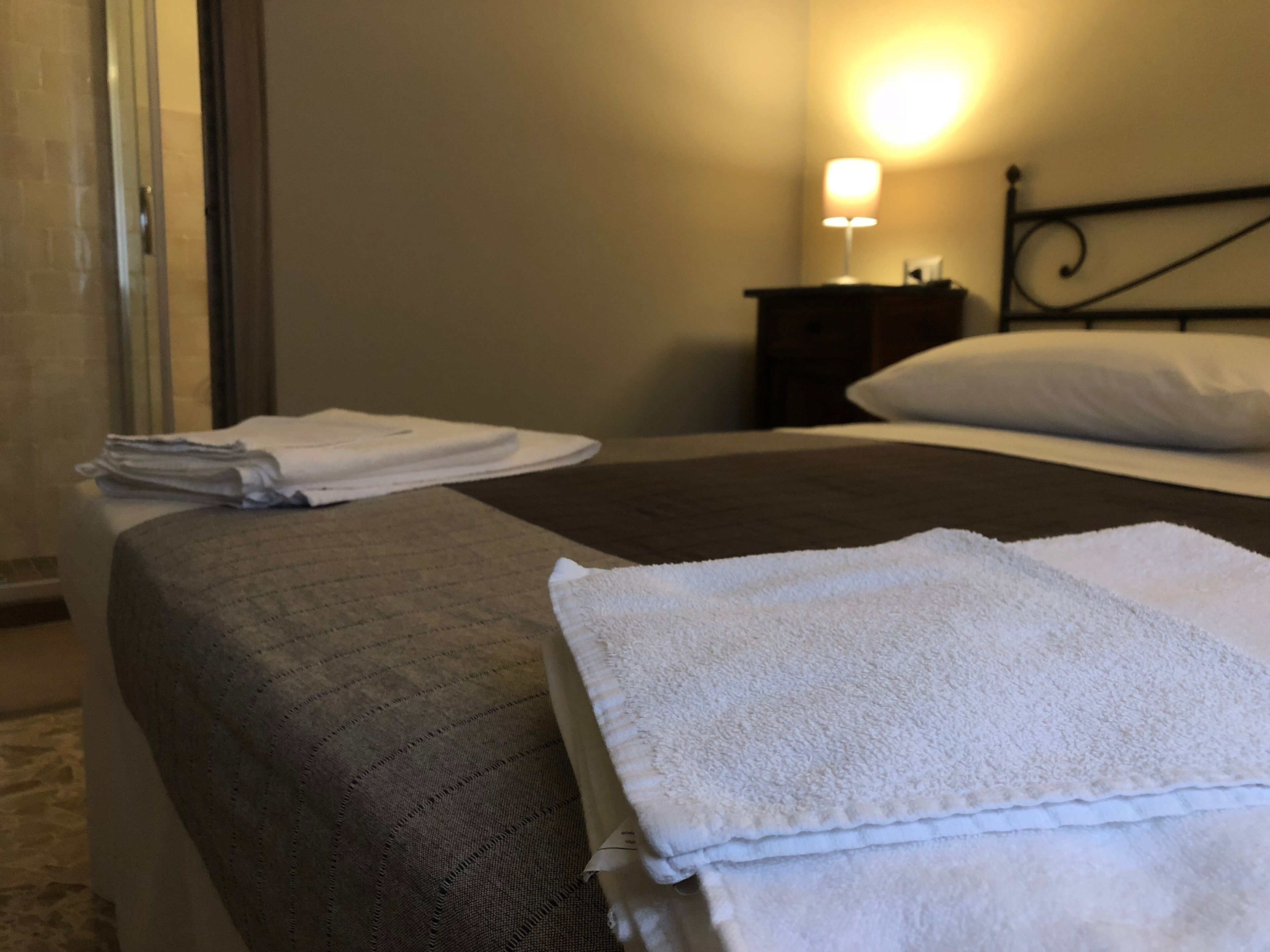 A neatly made bed with a gray and white duvet, a white pillow, and a folded white towel on the side.