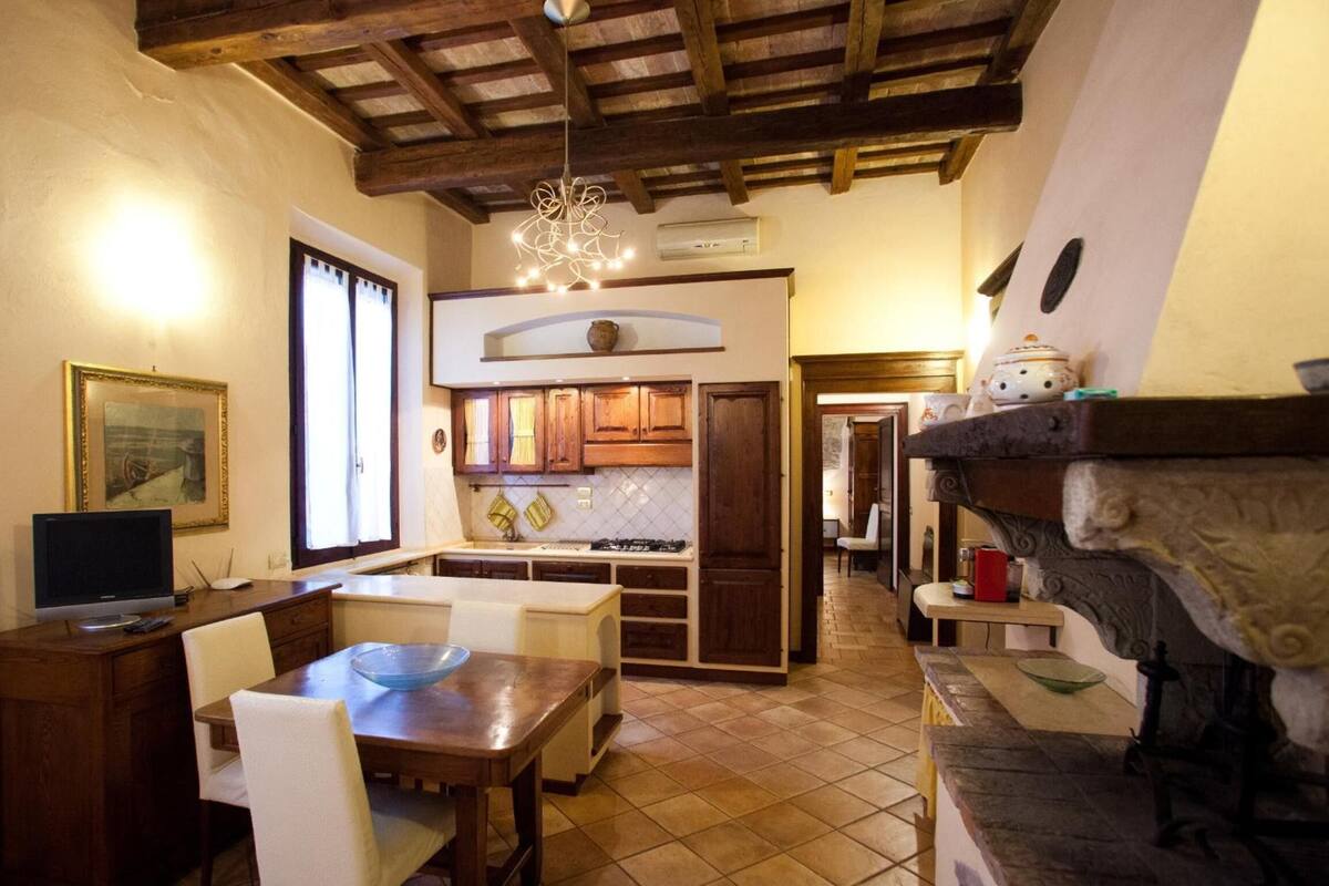 Una cocina acogedora con armarios de madera, una mesa de comedor con sillas y una lámpara colgante.