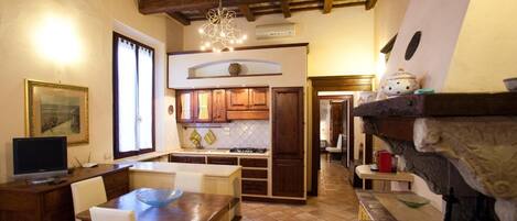 A cozy kitchen with wooden cabinets, a dining table with chairs, and a hanging light fixture.