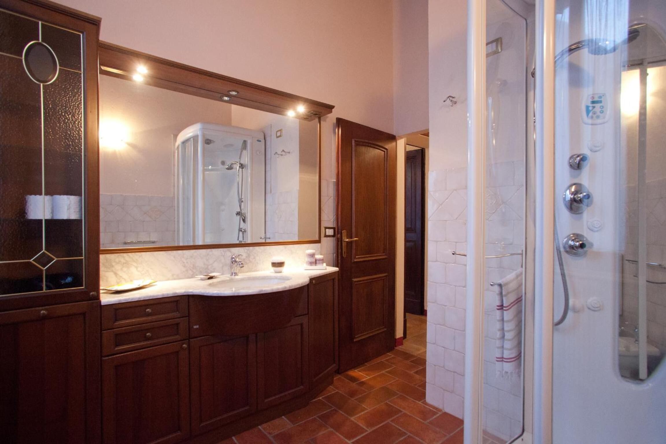 Une salle de bain dotée d’un grand miroir, d’un meuble-lavabo à deux vasques, d’une cabine de douche et d’un sol carrelé.