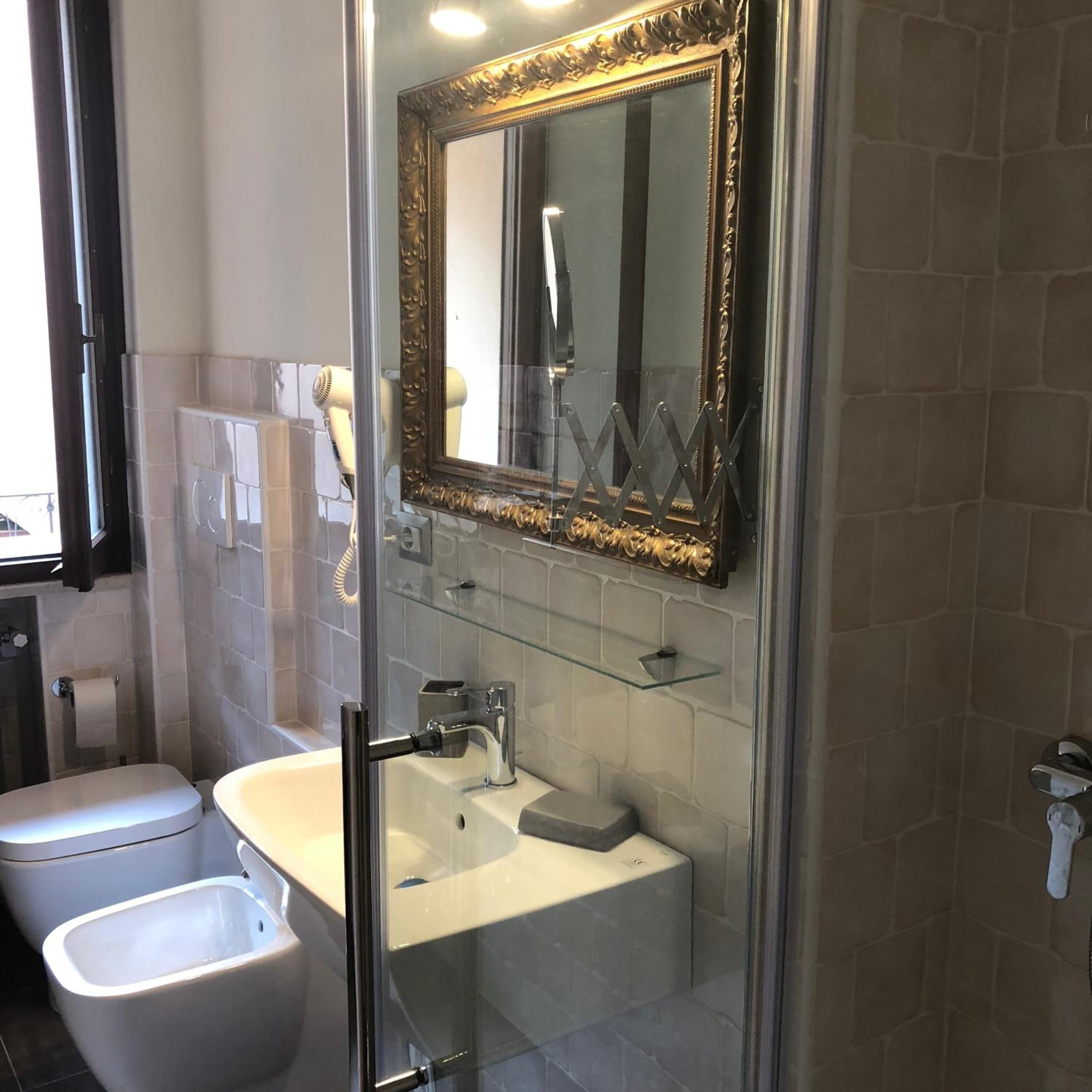 A modern bathroom with a glass shower enclosure, a white toilet, and a sink with a mirror above it.
