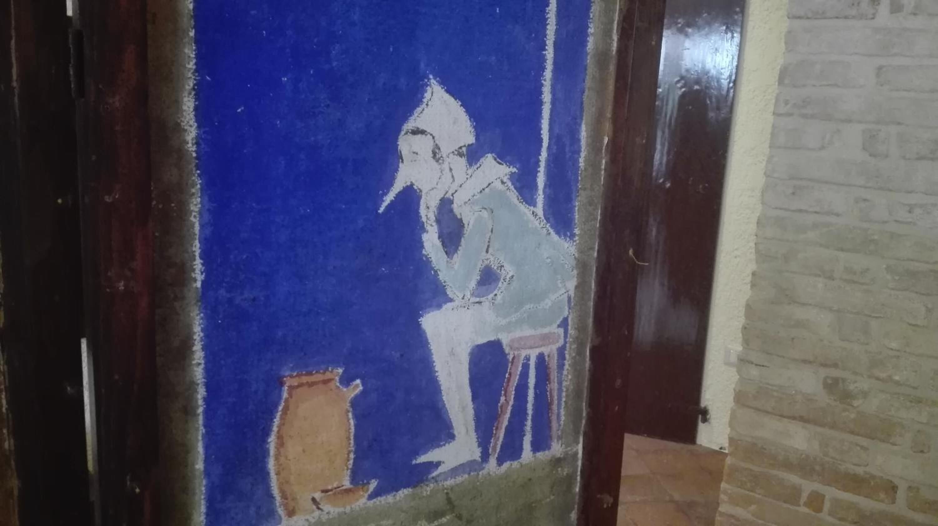 A blue wall with a white mural of a person and a pot.
