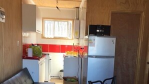Un espacio habitable compacto con kitchenette, sofá, mesa de comedor y una silla.