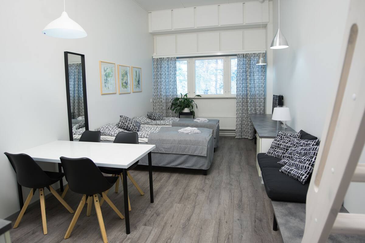 A modern bedroom with a bed, bedside table, and a desk with chairs.