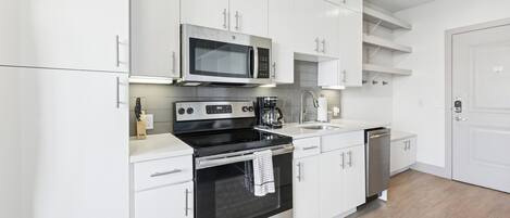 A modern kitchen with white cabinetry, a built-in microwave, a stove, and a dishwasher.