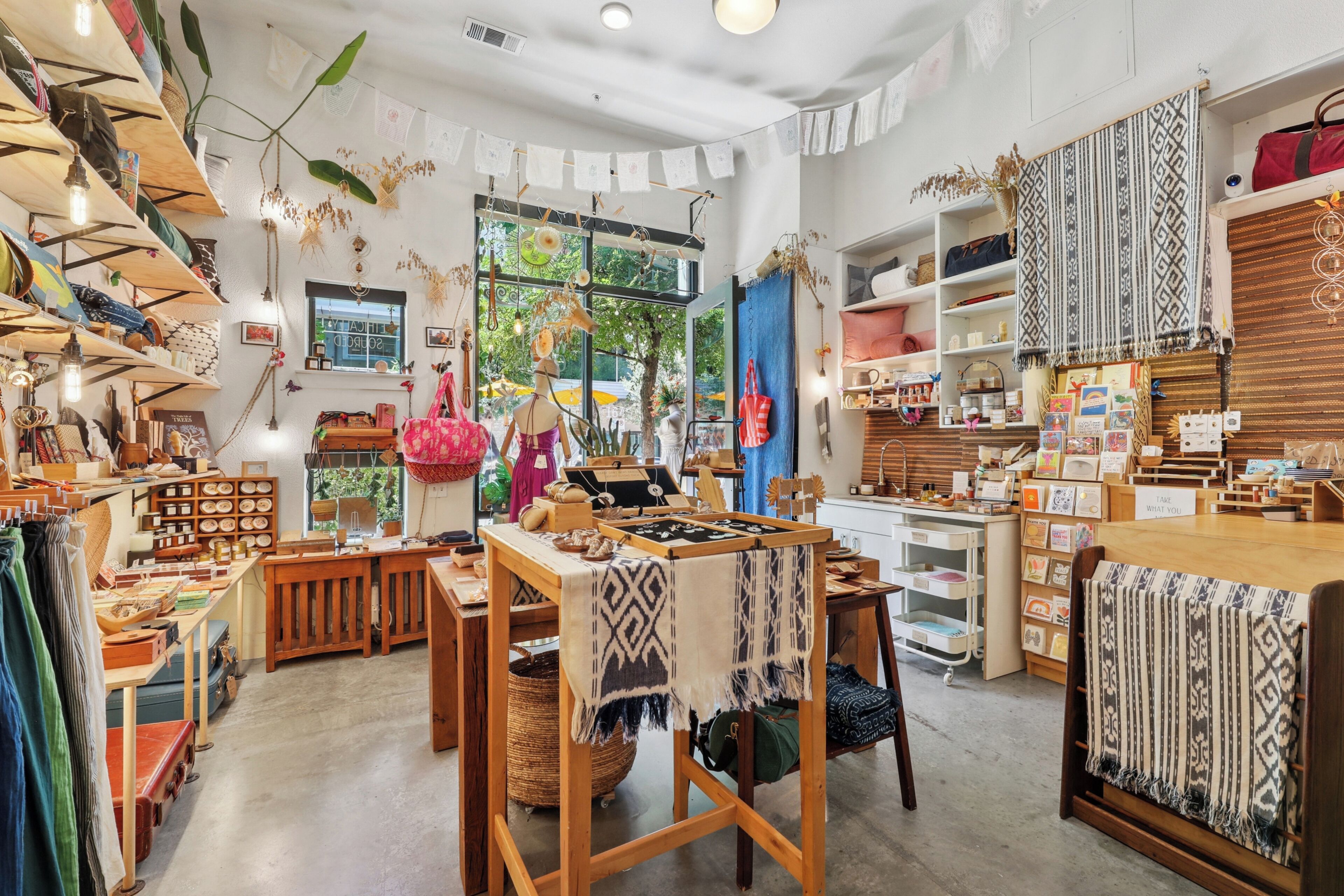 A boutique store with wooden shelves, tables, and hanging decorations.