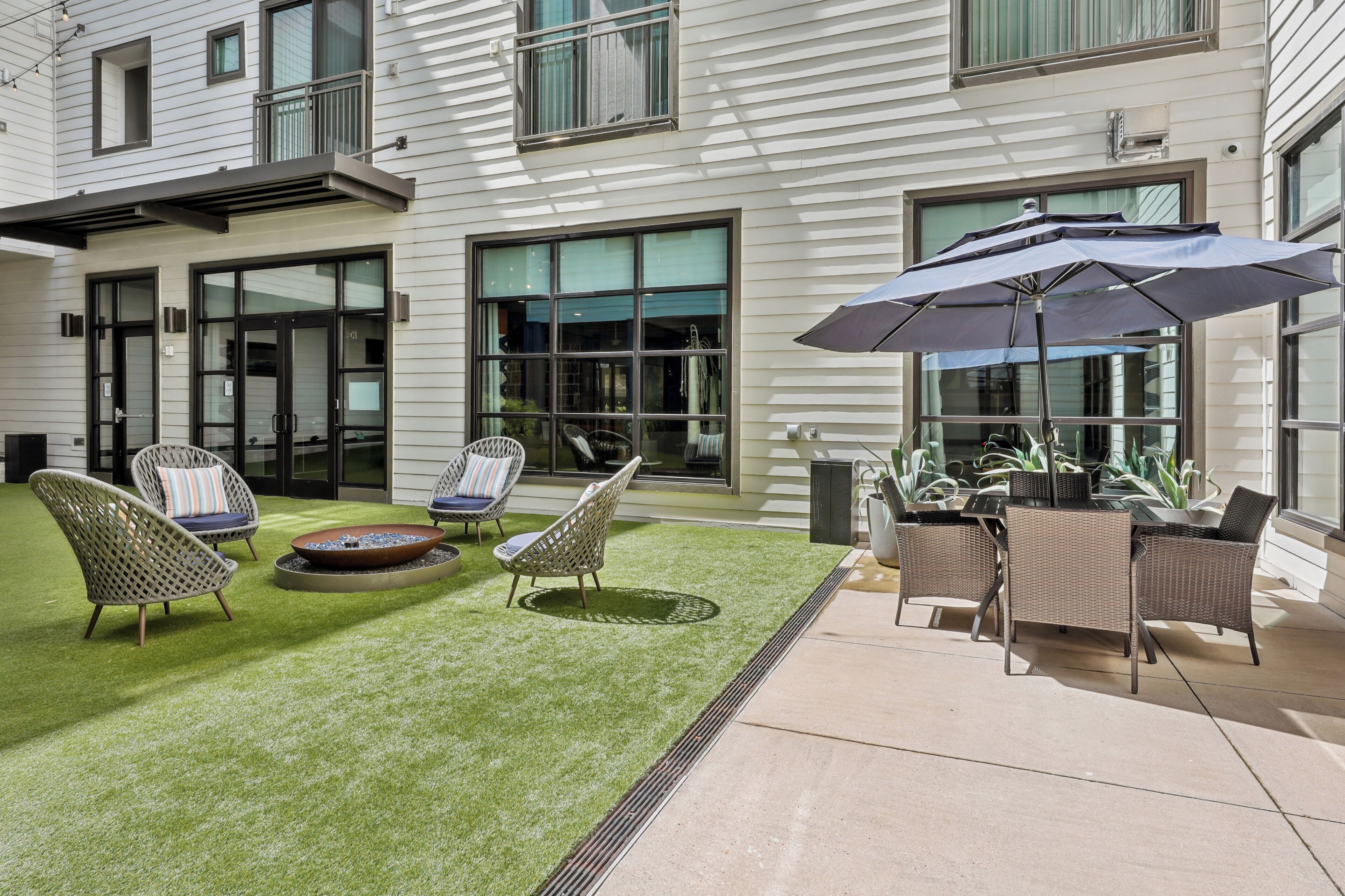 Un patio con mobiliario de mimbre, un hogar y una sombrilla grande.