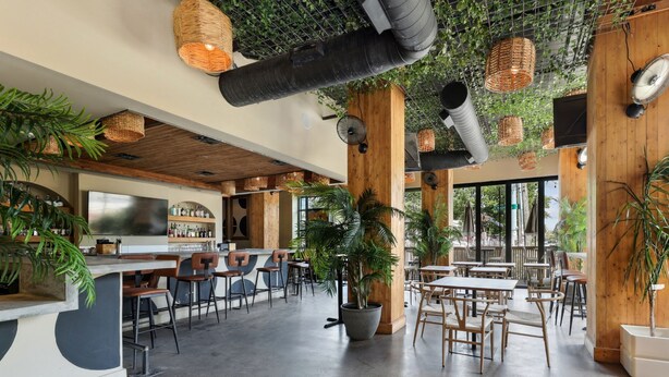 A modern bar area with wooden accents, a bar counter, and seating. - Sentral East Austin at 1630 E. Sixth (Austin)