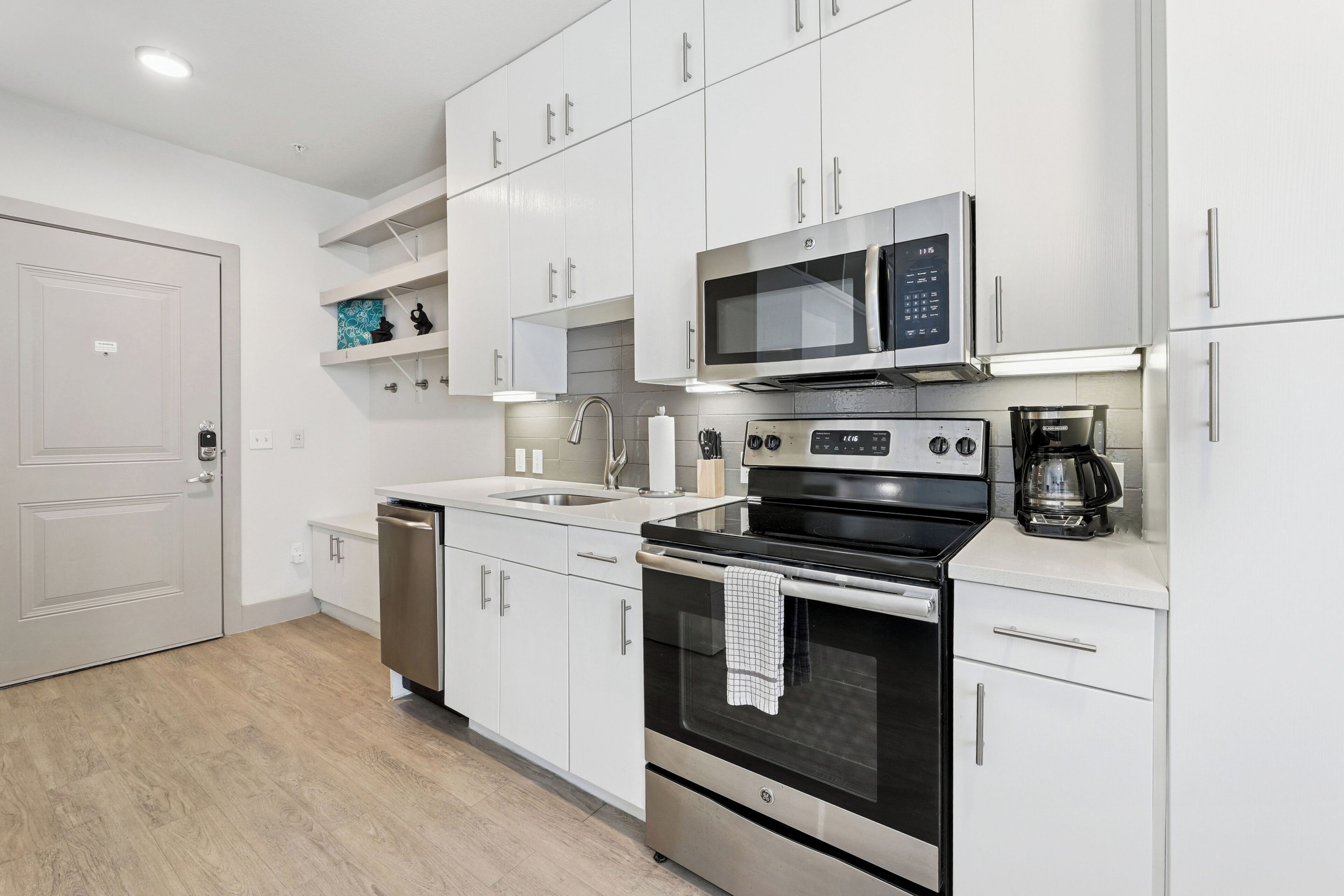 A modern kitchen with white cabinets, stainless steel appliances, and a dishwasher.