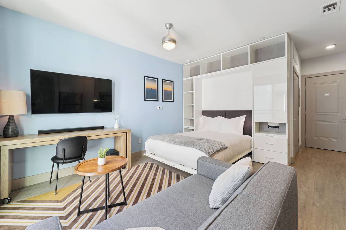 Une chambre d’hôtel moderne équipée d’un lit, d’un canapé, d’un bureau, d’une télévision et d’une armoire.