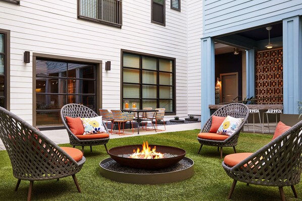 An outdoor seating area with wicker chairs and a central fire pit. - Sentral East Austin at 1630 E. Sixth (Austin)