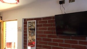 Ein Zimmer mit Ziegelwand, einem flachbildfernseher über einer roten Bank und einer hängenden Pendelleuchte.