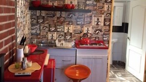 Eine kleine Küche mit roter Arbeitsplatte, einer gelben Pendelleuchte und einer Wand mit Muster.