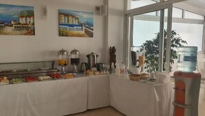 A buffet setup with various food items and beverages, a water dispenser, and two paintings on the wall. - Ceko Hotel (Sarandë)
