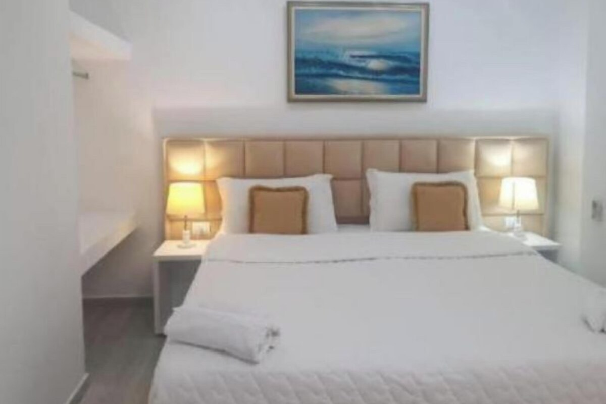 Une chambre d’hôtel avec un lit, des tables de chevet, un tableau et une vue sur la mer.