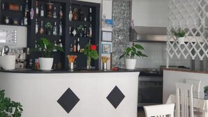 A kitchen with a bar area, white cabinets, and various kitchen appliances. - Ceko Hotel (Sarandë)