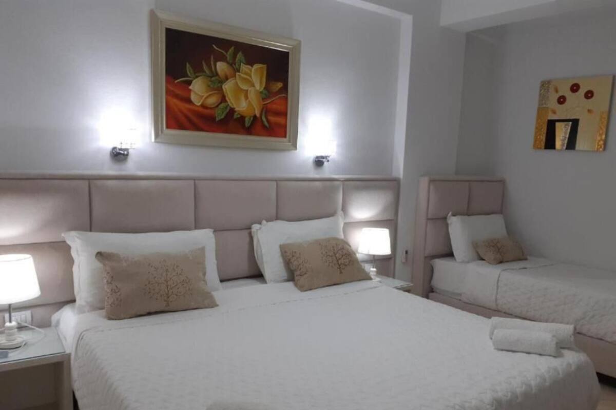 A hotel room with a large bed, two bedside tables, and a painting on the wall.