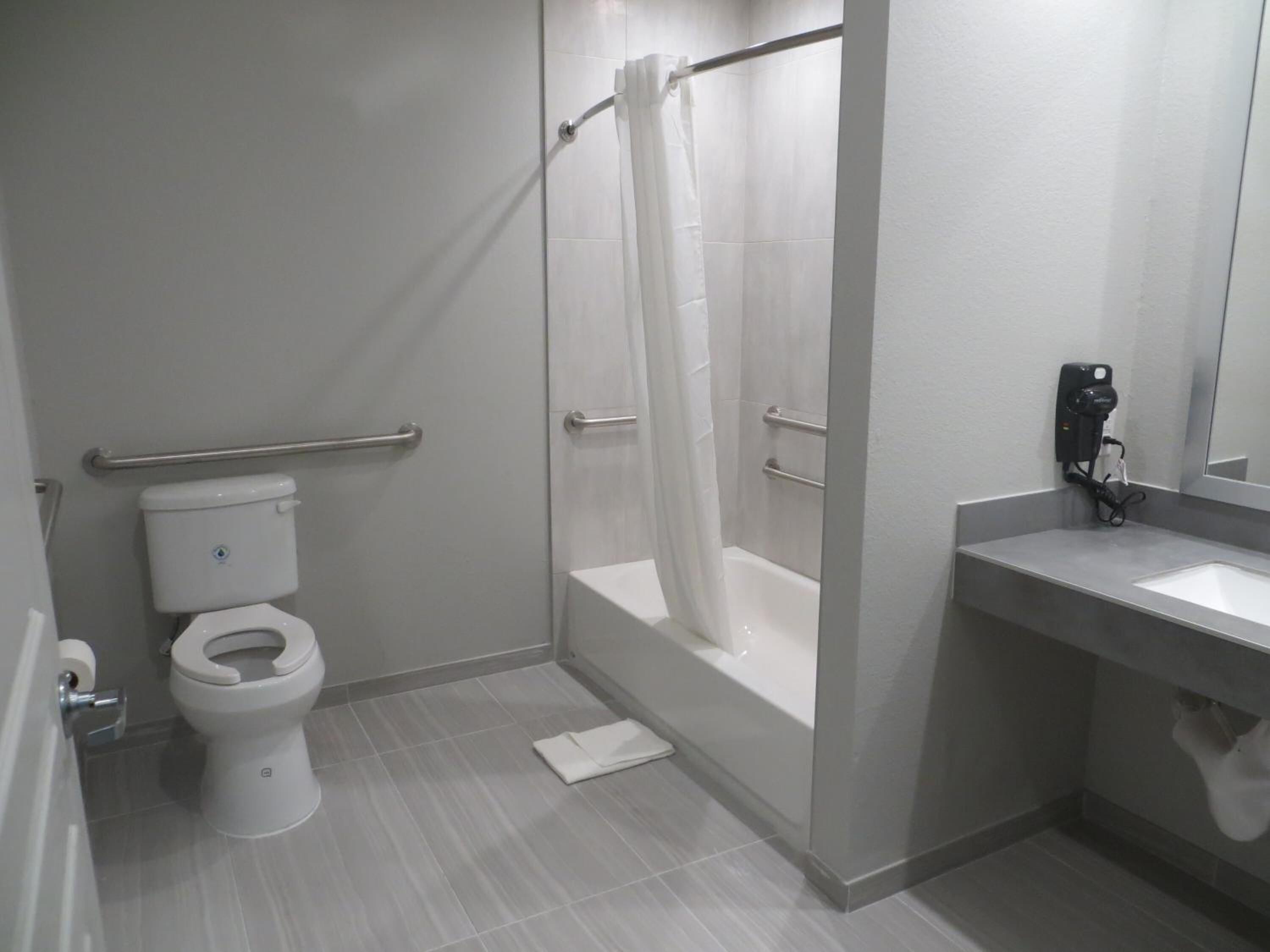 A modern bathroom with a toilet, shower, and sink.