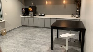 Una cuina moderna amb armaris grisos, una màquina de cafè i llums penjants.