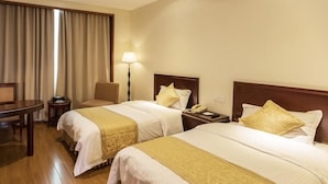 Quarto de hotel com duas camas, uma mesa, uma cadeira, um abajur e um telefone na mesa de cabeceira.