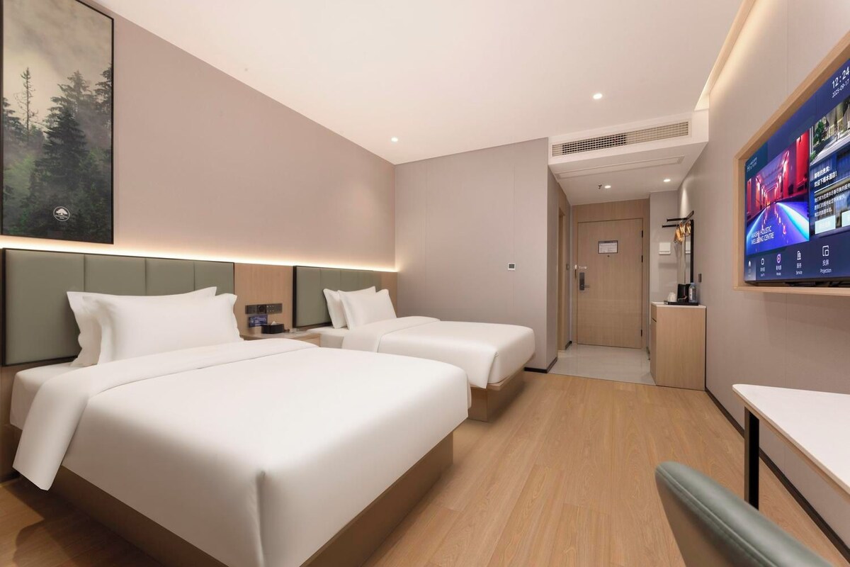 Ein Hotelzimmer mit zwei Betten, einem Fernseher und einem Schreibtisch.