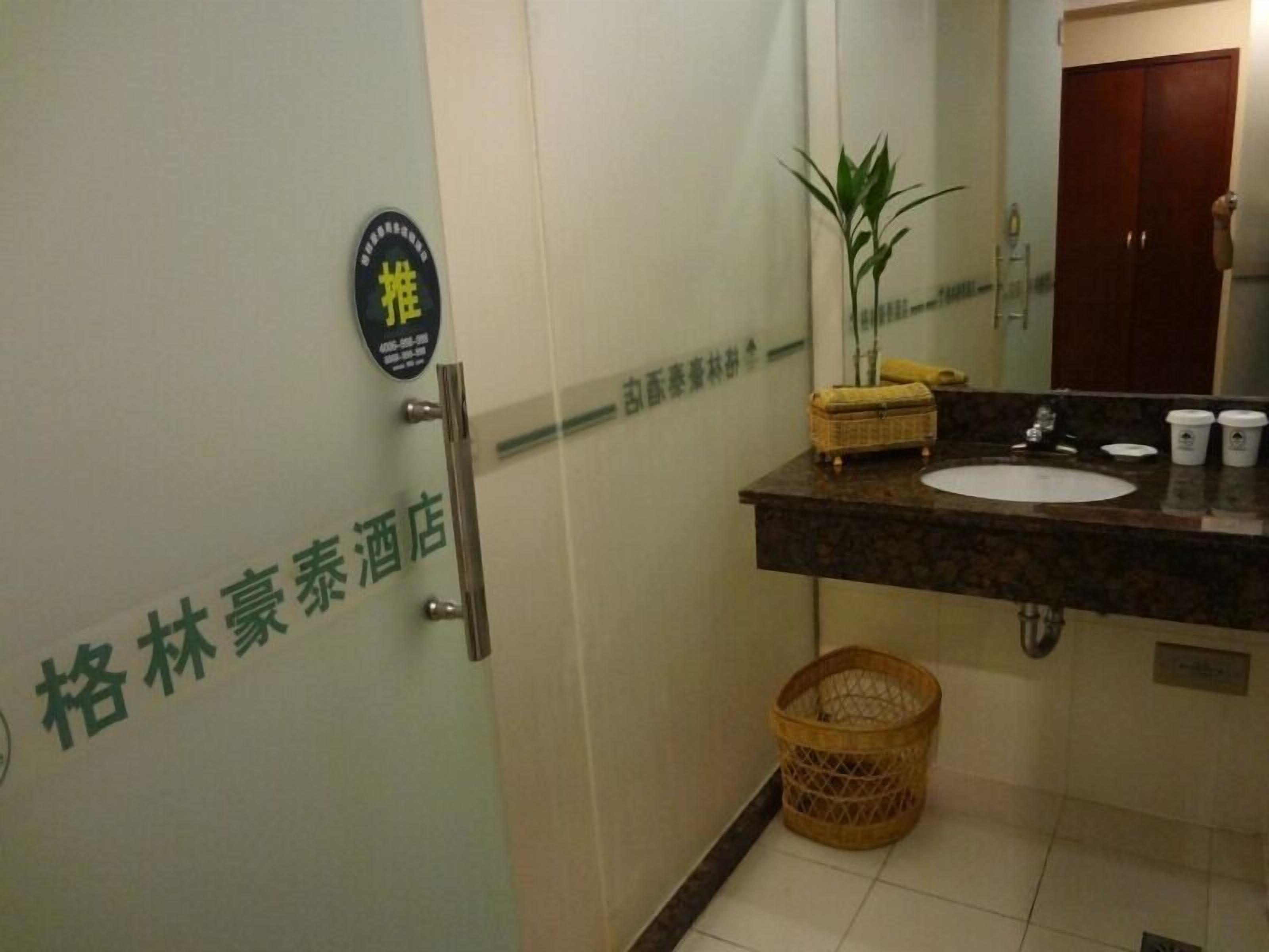 Un baño de hotel con lavabo, espejo y cubo de basura.