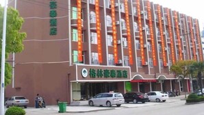 A multi-story hotel with a prominent green sign on the facade. - GreenTree Inn Nantong Tongzhou Bus Station Express Hotel (Nantong)