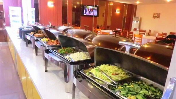 Una barra de buffet con diversas opciones de comida, como arroz, verduras y otros platos.