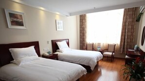 Una habitación de hotel con dos camas, un escritorio, una silla y una planta en maceta.