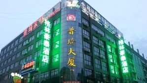 Un edificio de varios pisos con letreros iluminados que indican diversos comercios, incluyendo un hotel y un restaurante.