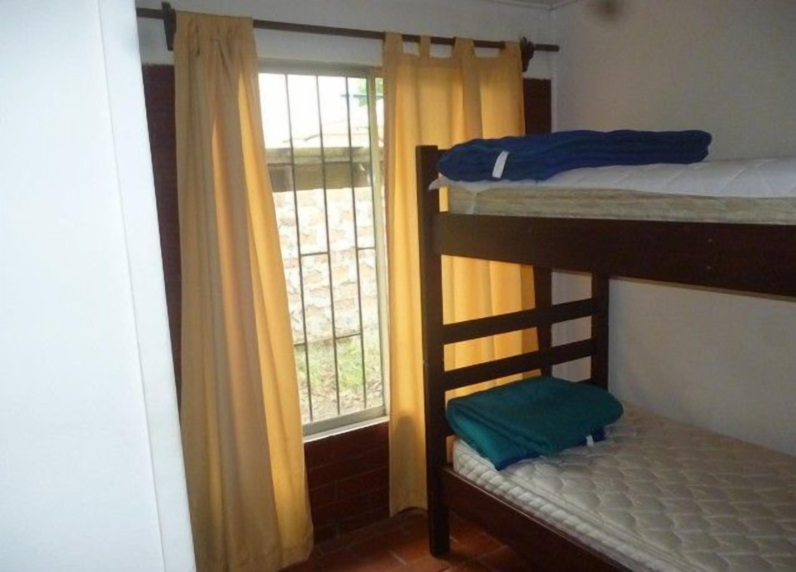 Una camera con un letto a castello, una finestra e tende.