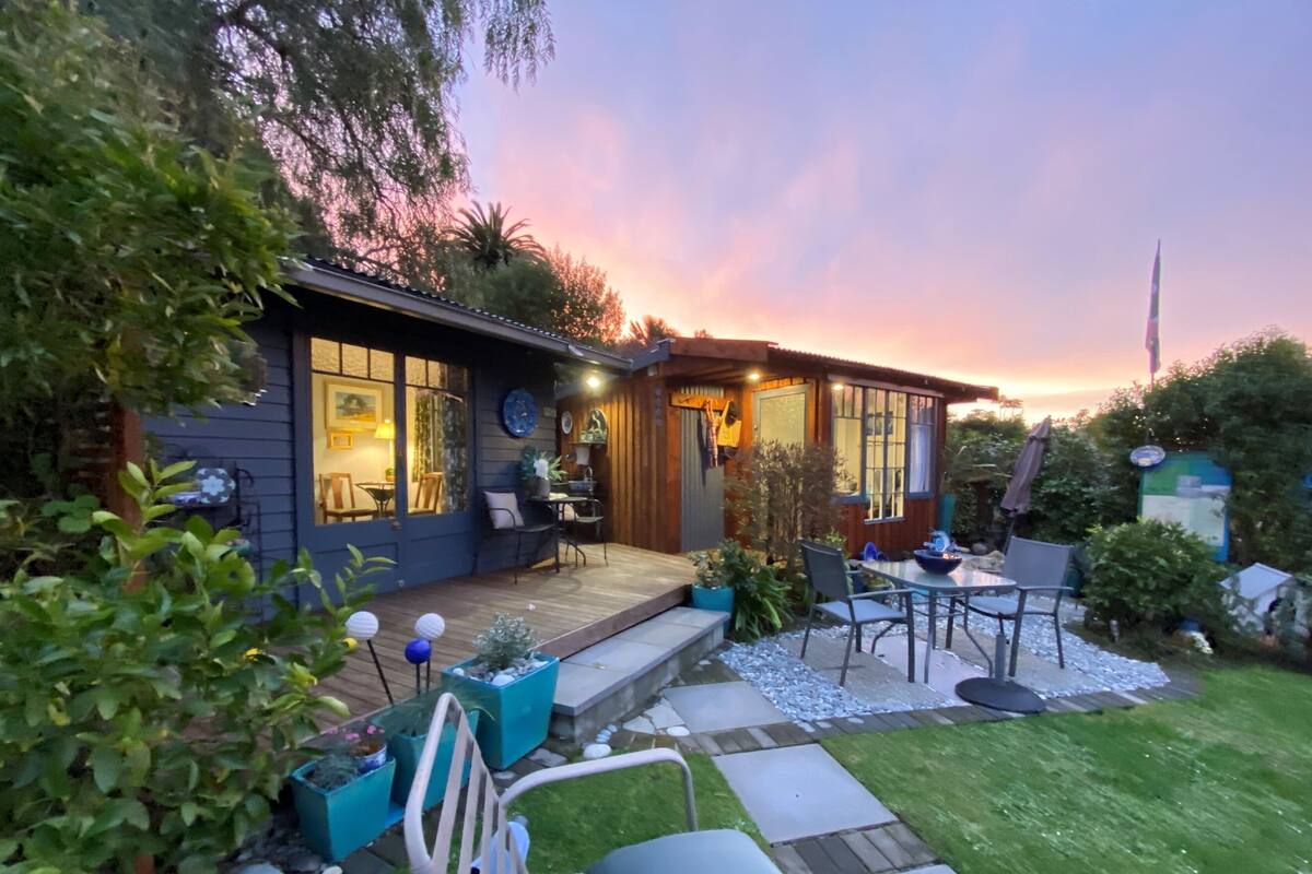 A modern house with a deck, outdoor seating, and a well-maintained garden.