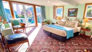 Un dormitorio espacioso con una cama grande, vistas al jardín a través de puertas correderas y una zona de descanso acogedora con una silla y una mesa.
