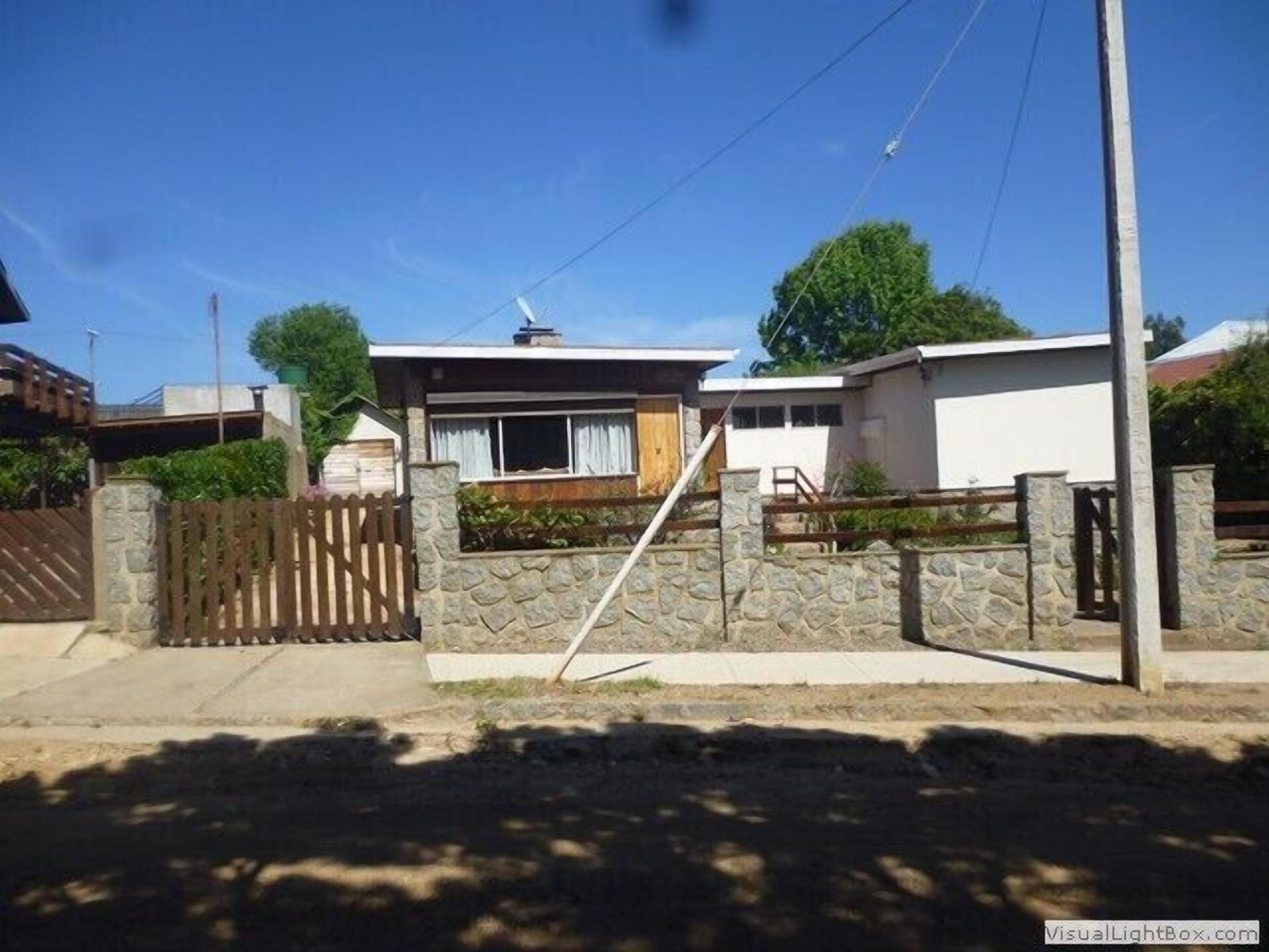 A residential property with a stone wall gate, a wooden fence, and a small porch.