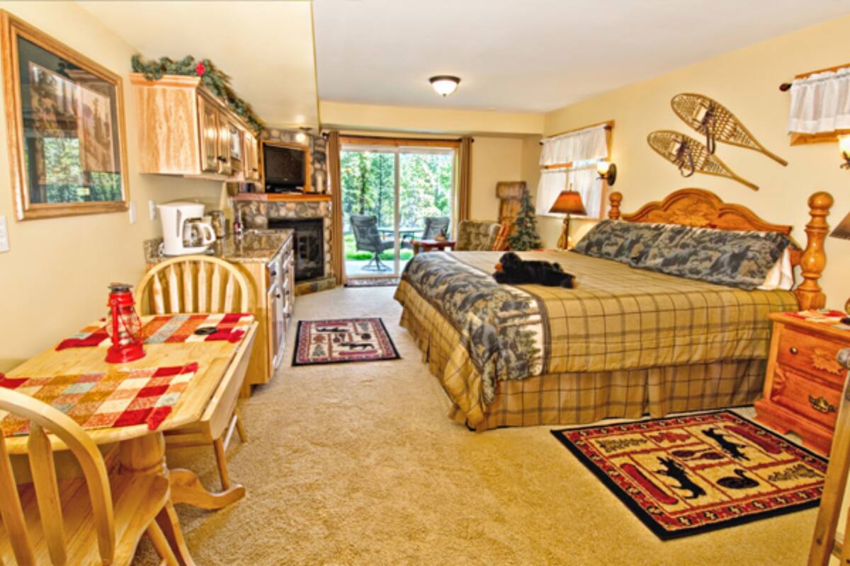 A cozy bedroom with a bed, a desk, and a chair. There is a window with a view of greenery outside.