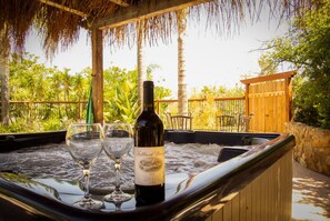 Un jacuzzi con una botella de vino y dos copas sobre el capó de un coche.