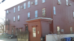 A two-story red brick building with multiple windows, a garage door, and a small porch area. - Bellevue House (Newport)