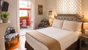 A bedroom with a large bed, bedside lamps, a TV, a chair, and a view of the outside. - Bellevue House (Newport)