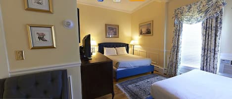 Una habitación de hotel con cama, mesita de noche, lámpara y cuadros en la pared.