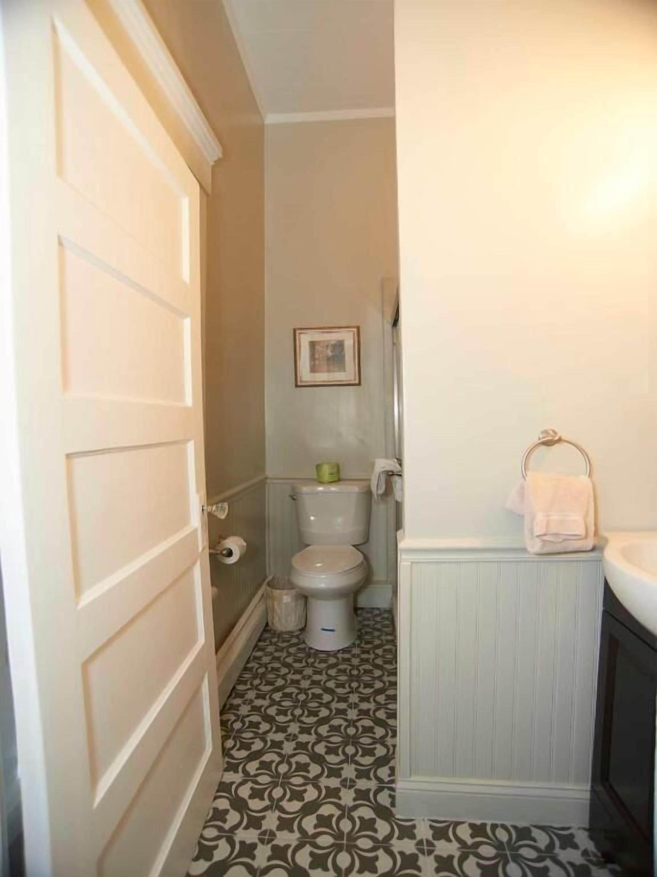 Une salle de bain avec des toilettes, un lavabo et des carreaux de sol à motifs.