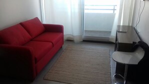 A red sofa, a small table, and a view of a balcony. - Depto La Herradura Coquimbo 974 (Coquimbo)
