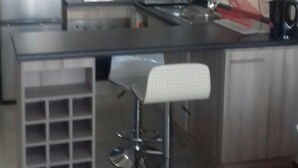 A modern kitchen with a central island, bar stools, and built-in appliances. - Depto La Herradura Coquimbo 974 (Coquimbo)