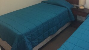 A small, single-bed room with a blue bedspread, a wooden headboard, a nightstand with a lamp, and a wall poster. - Depto Laguna del Mar La Serena 975 (La Serena)
