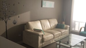 A living room with a beige sofa, a glass coffee table, and wall art. - Depto Laguna del Mar La Serena 975 (La Serena)